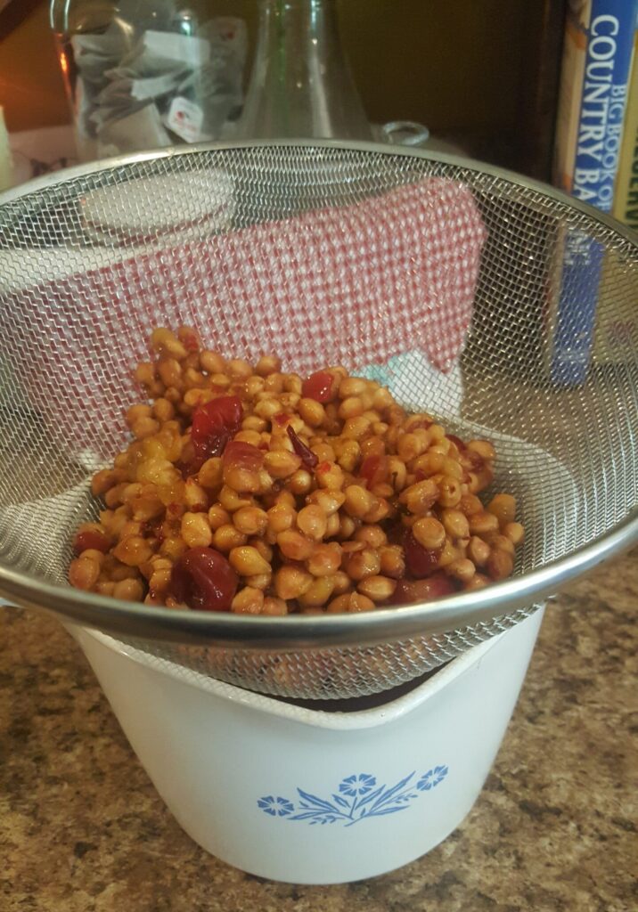 draining the bowl of cherries seed thru a sieve to gather the cherry juice