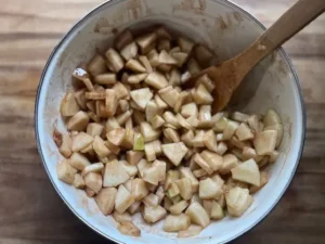 cut up apples in a large bowl with spices and sauce