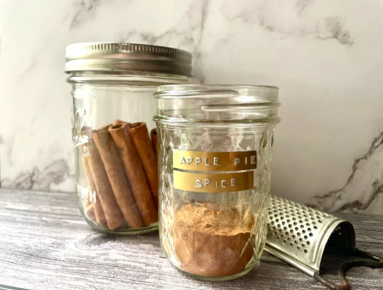 Jar of homemade apple pie spice mix with a rustic farmhouse feel, ideal for adding cozy fall flavor to seasonal recipes.