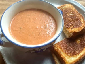 Easy Creamy Roasted Tomato Soup made with fresh garden tomatoes, onion, and garlic. A cozy, comforting soup perfect for summer harvest or chilly fall nights. Pin this recipe for delicious homemade soup to warm up with!