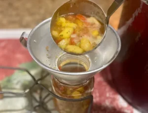filling canning jars Peach salsa with tomatoes