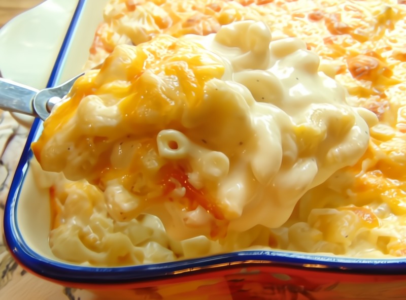 a spoonful of creamy Mac and cheese being lifted out of casserole
