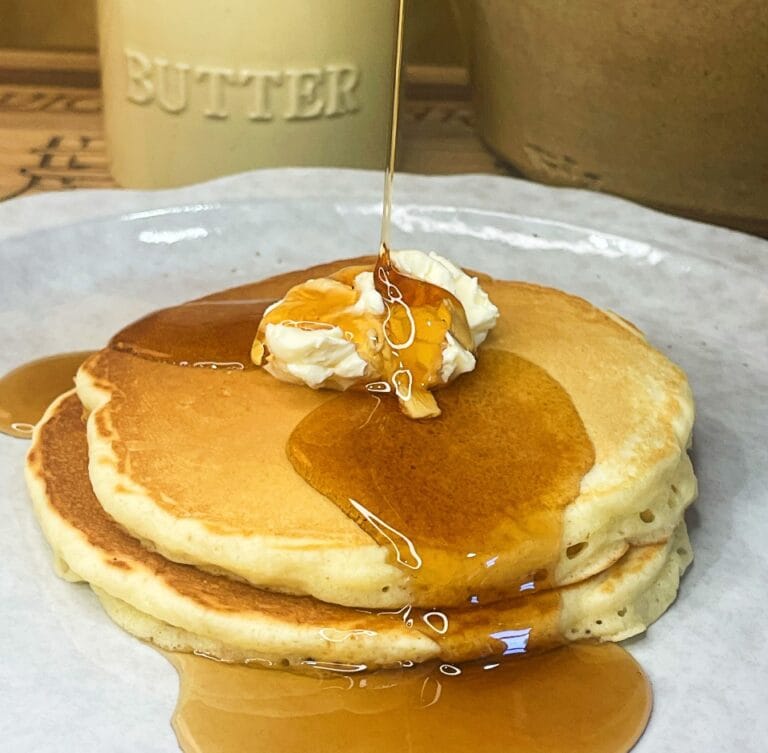 easy homemade pancakes stacked on a plate with butter and syrup