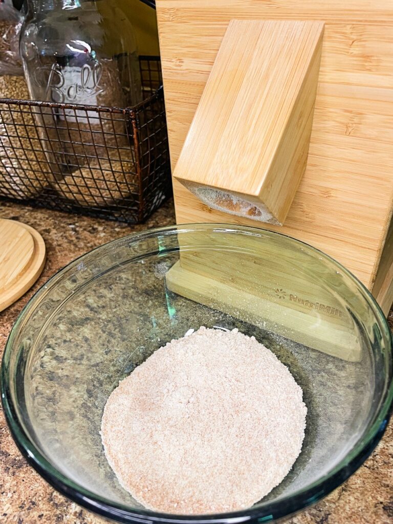 fresh milled flour in a bowl in front of a grain mill