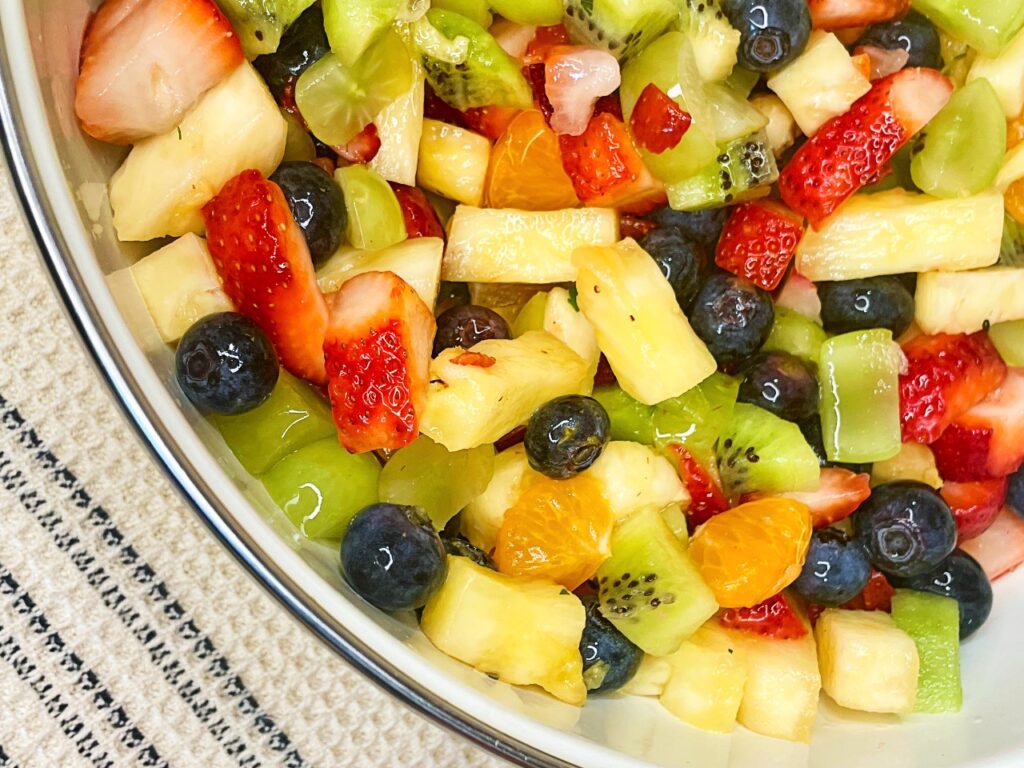 Fresh fruit salad with strawberries, blueberries, kiwi, pineapple, and grapes in a serving bowl.