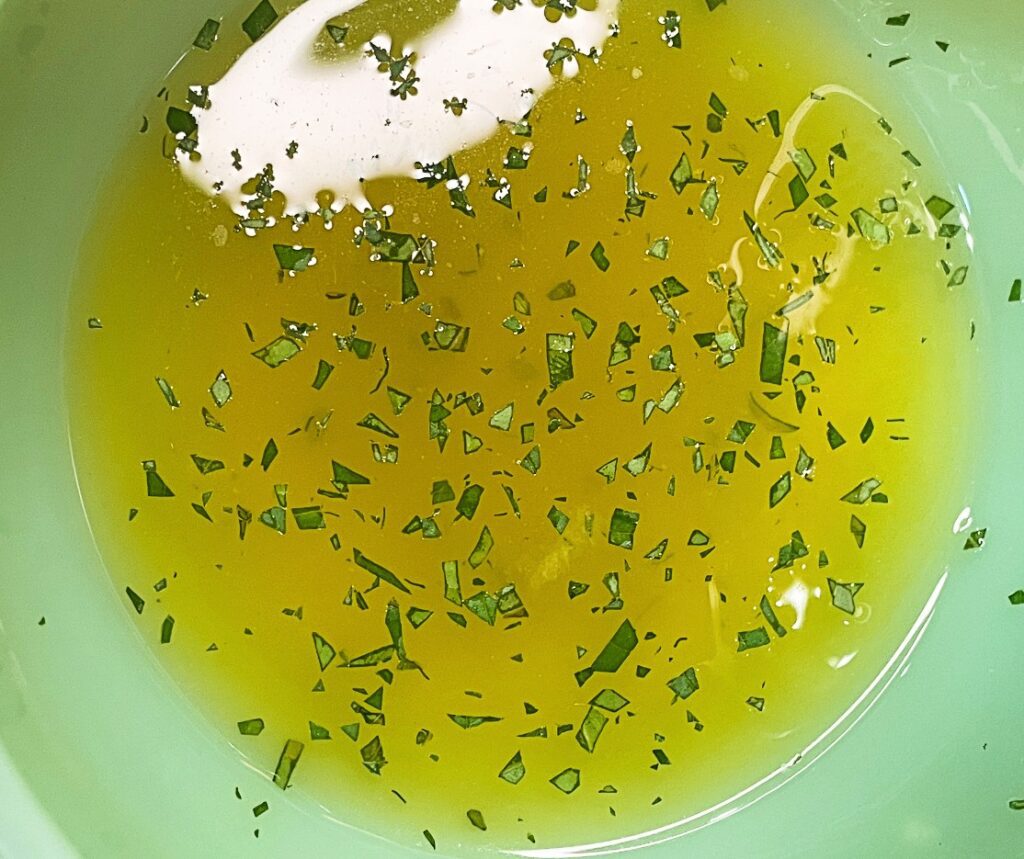 Honey lime dressing being poured over a colorful summer fruit salad.