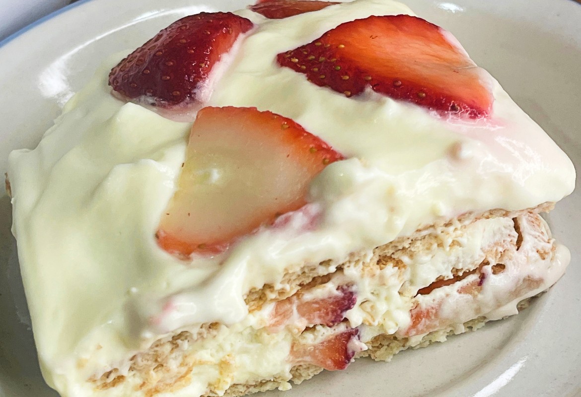 Strawberry icebox cake layered with graham crackers, vanilla pudding, whipped cream, and fresh strawberries.