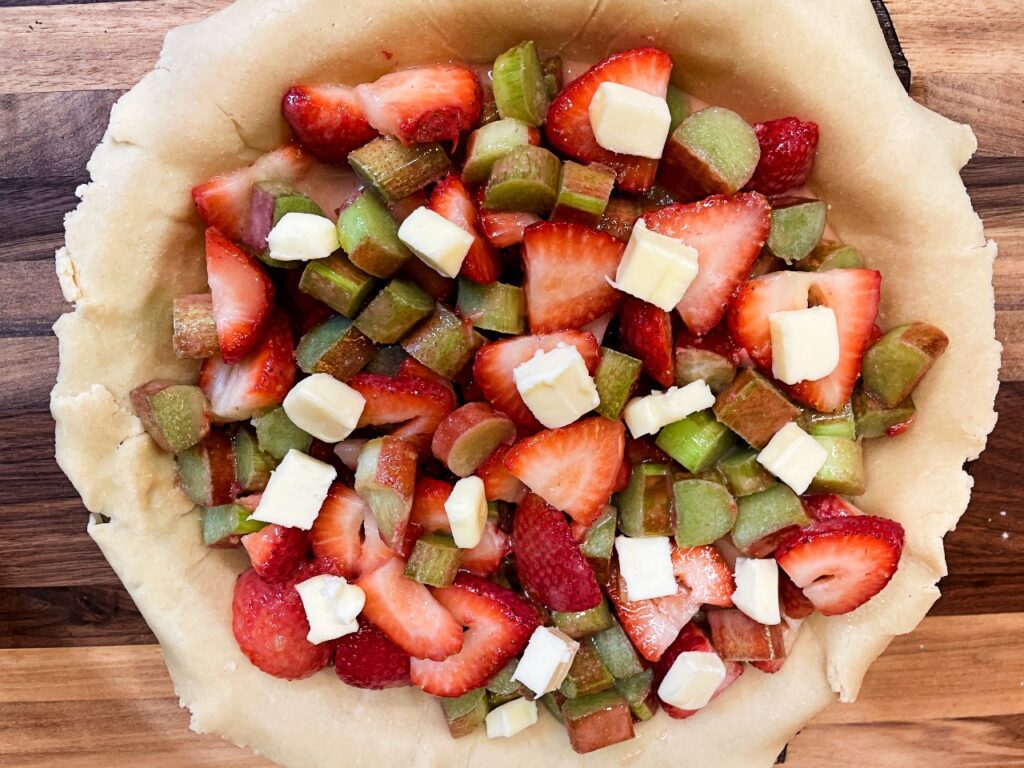 pie filling dotted with butter to make a rich strawberry rhubarb pie