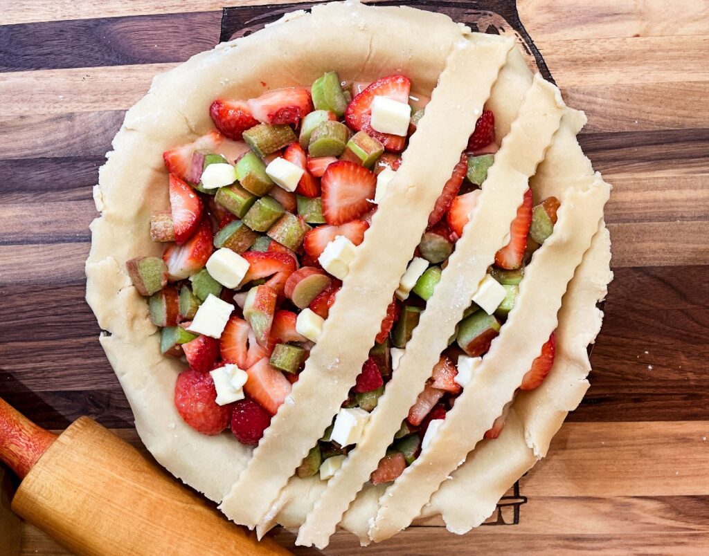 lattice top being placed on top of strawberry rhubarb pie filling