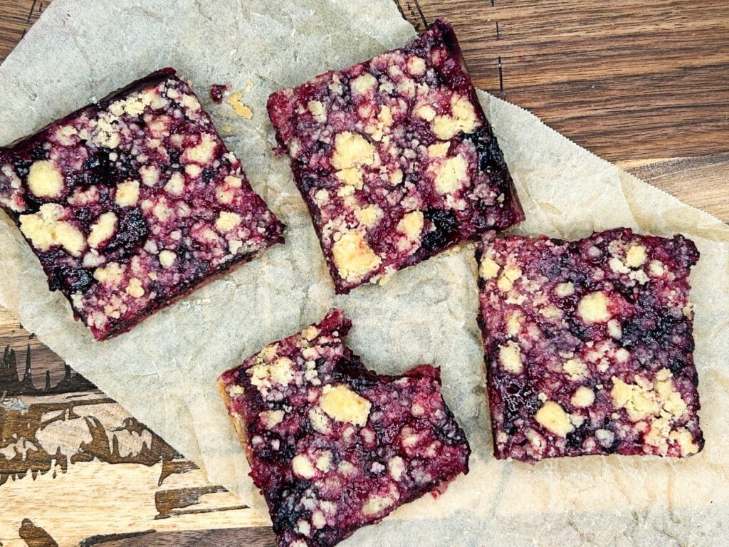 black raspberry crumble bars cut into serving size squares. one has a bit taken out of it