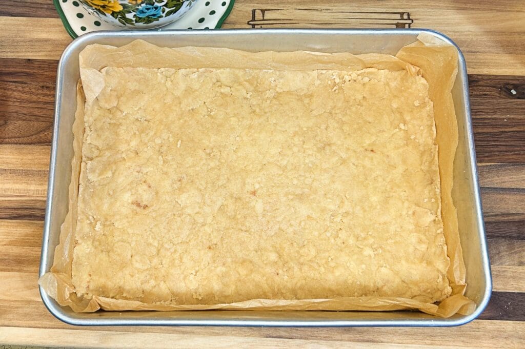 part of the crumble mixture pressed into prepared baking dish