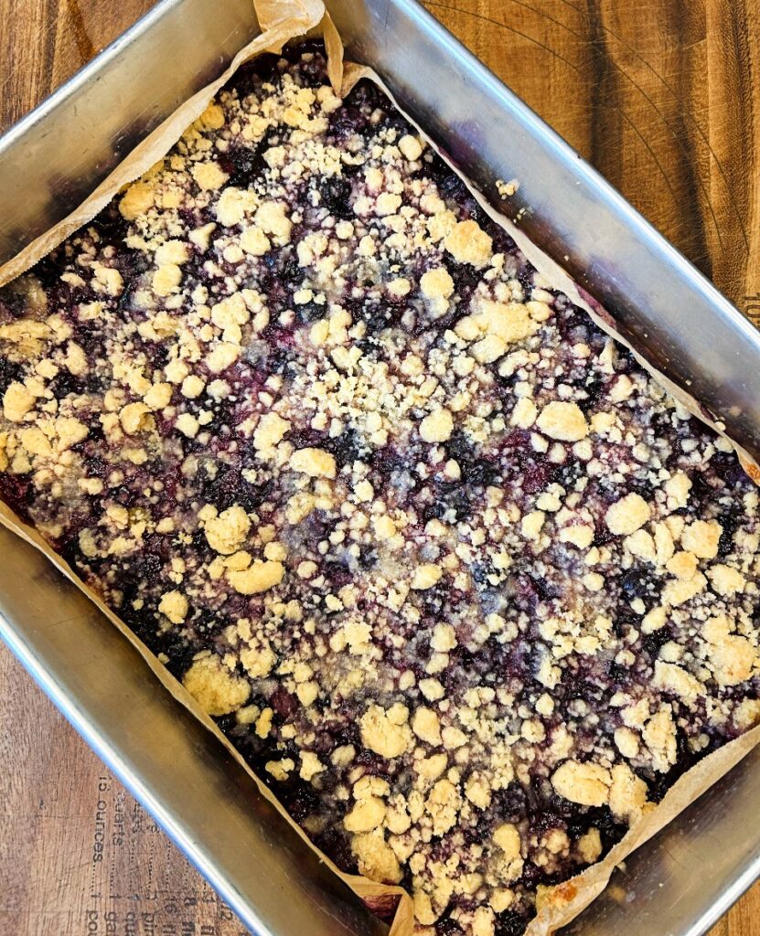 Blueberry crumble bars fresh from the oven with bubbling blueberry filling around the edges.