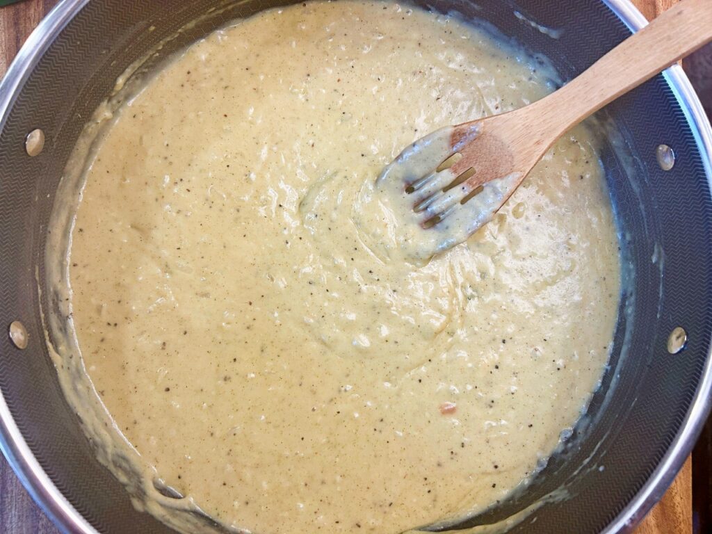 Homemade garlic herb cream sauce simmering in a skillet now thickened
