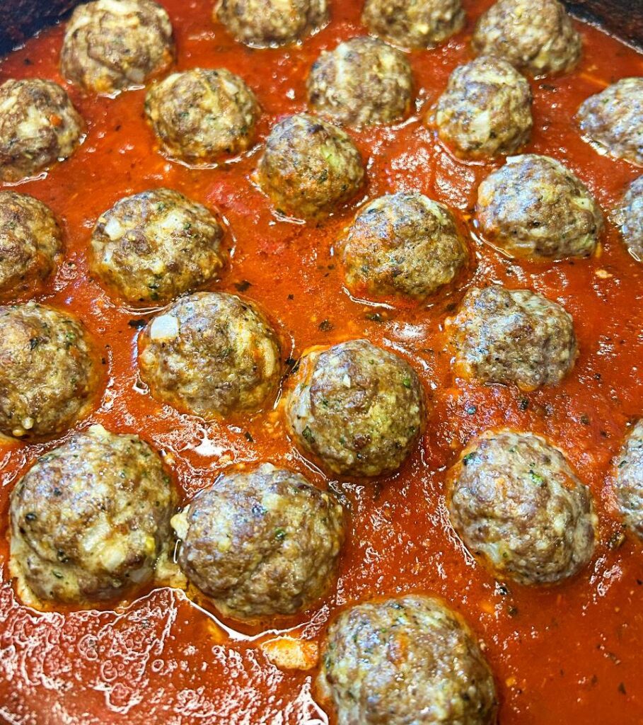 Baked homemade meatballs served with marinara sauce and Parmesan cheese.