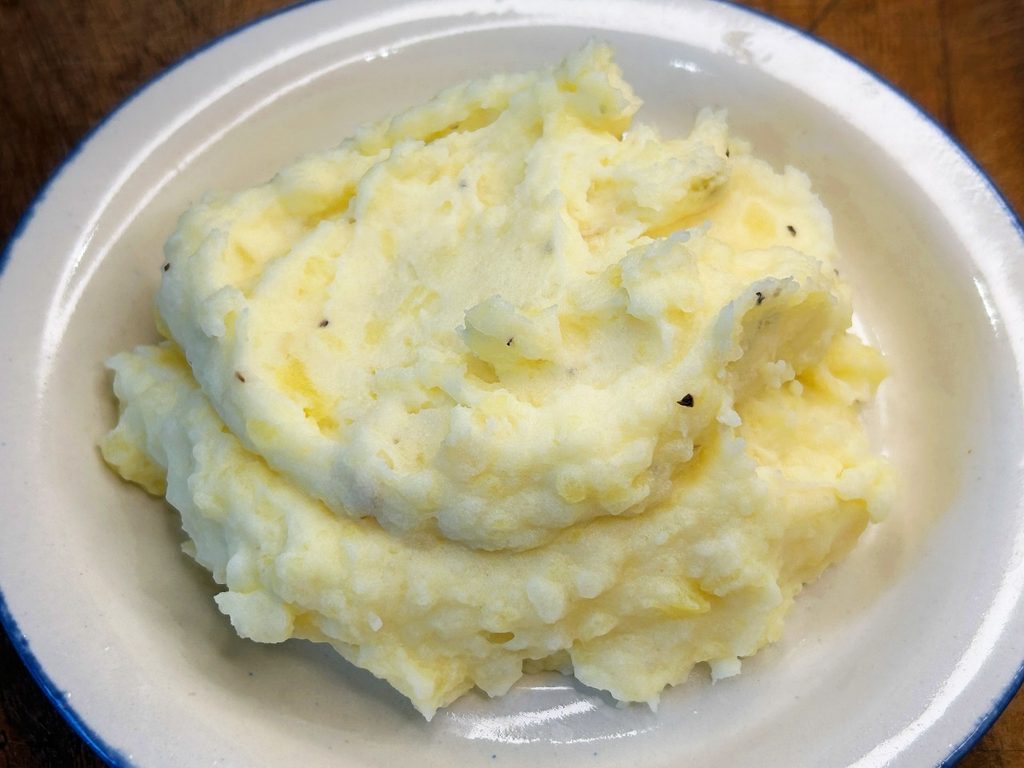 Creamy mashed potatoes in a serving bowl with melted butter on top