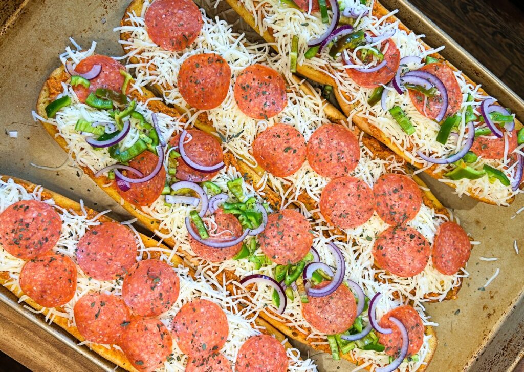 shredded mozzarella sprinkled over the sauce with pepperoni, thinly sliced bell peppers, and thinly sliced red onion.