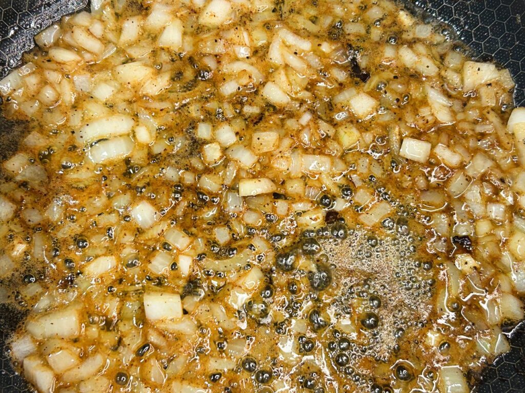Diced onions cooking in bacon drippings in a Dutch oven