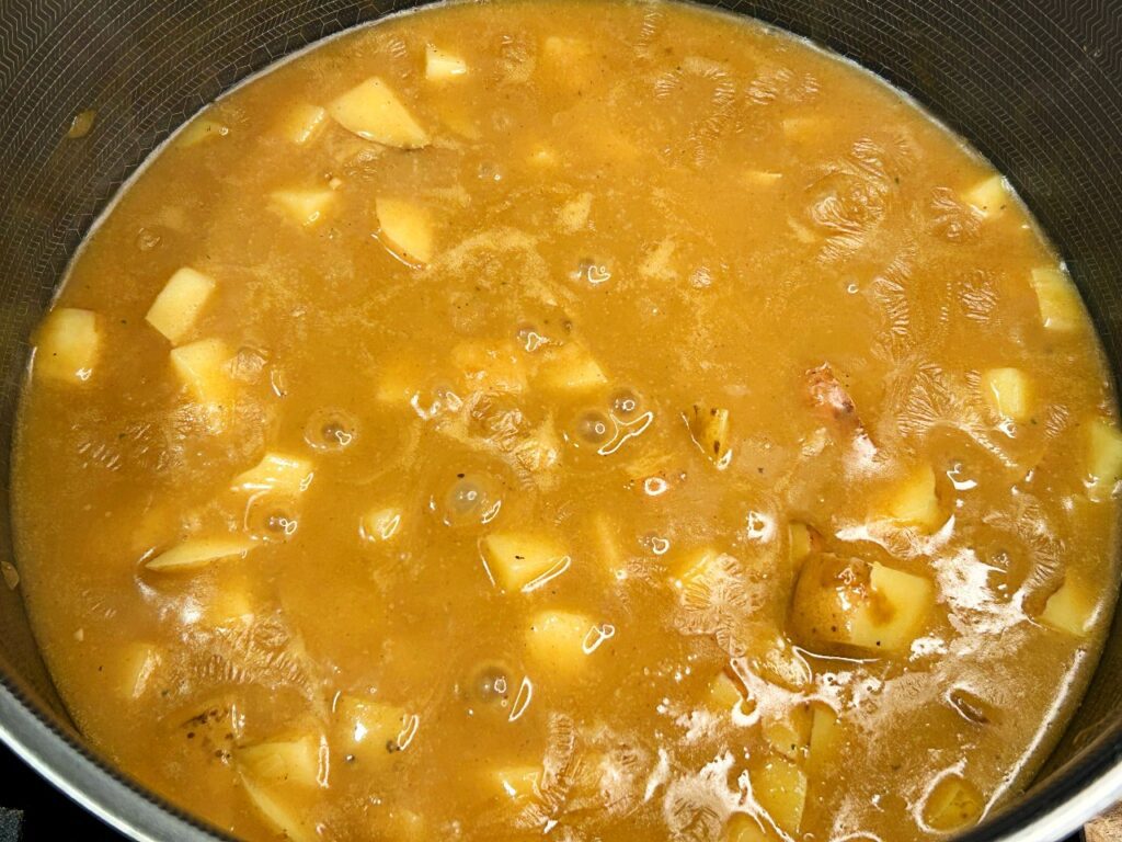 Diced potatoes simmering in chicken broth while making loaded potato soup