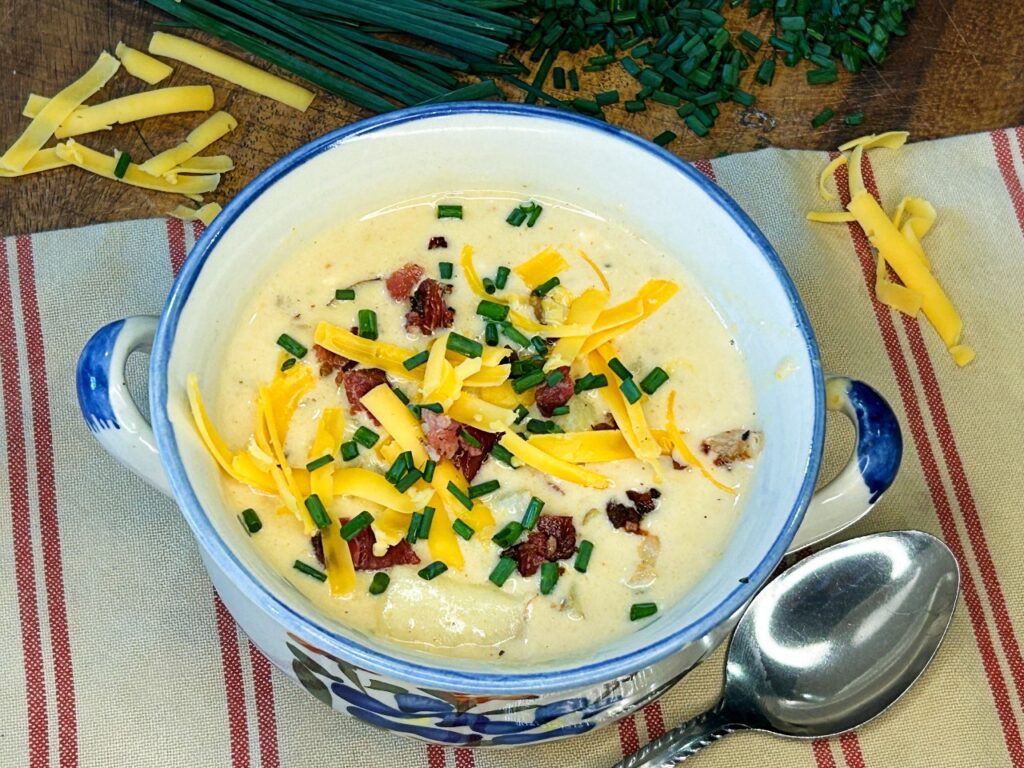 Close-up of creamy loaded potato soup with chunks of tender potatoes, bacon, cheddar, and chives
