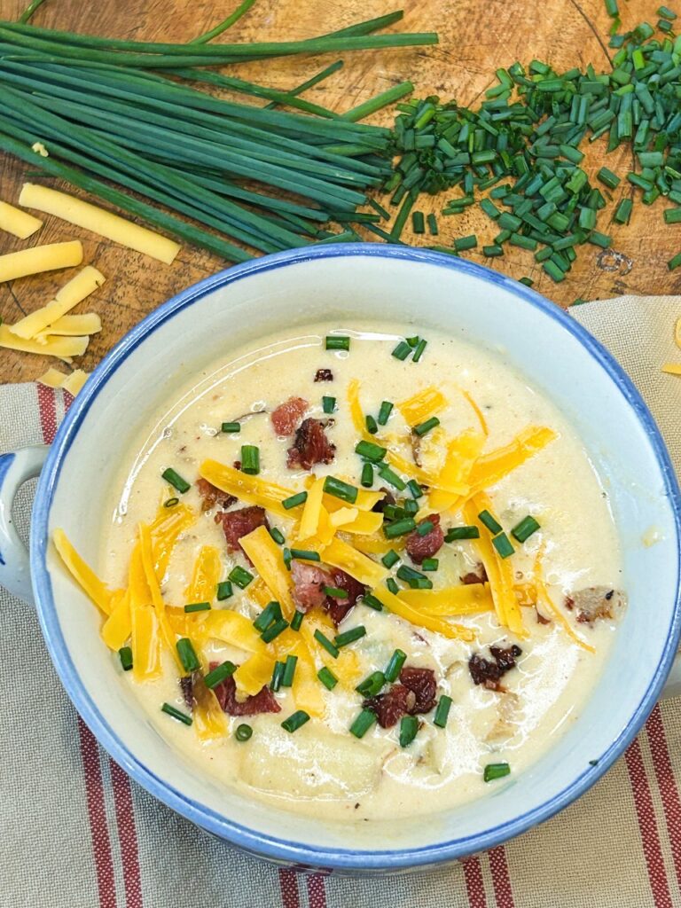 Close-up of creamy loaded potato soup with chunks of tender potatoes, bacon, cheddar, and chives
