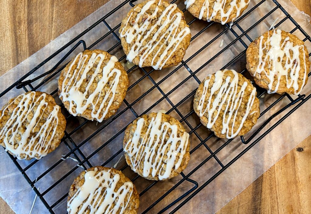 Maple pecan oatmeal cookies arranged on a cooling rack after glazing.