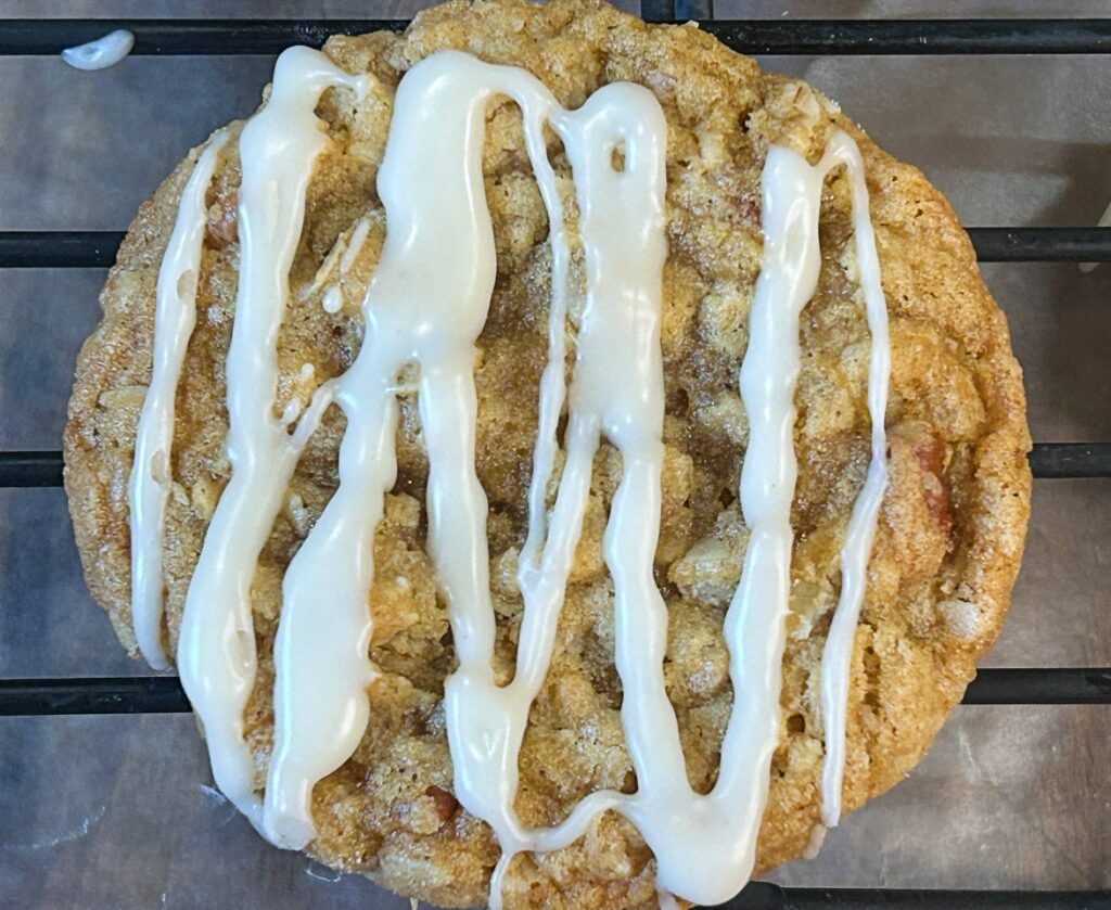 Close-up of a chewy brown butter maple oatmeal cookie with toasted pecans.