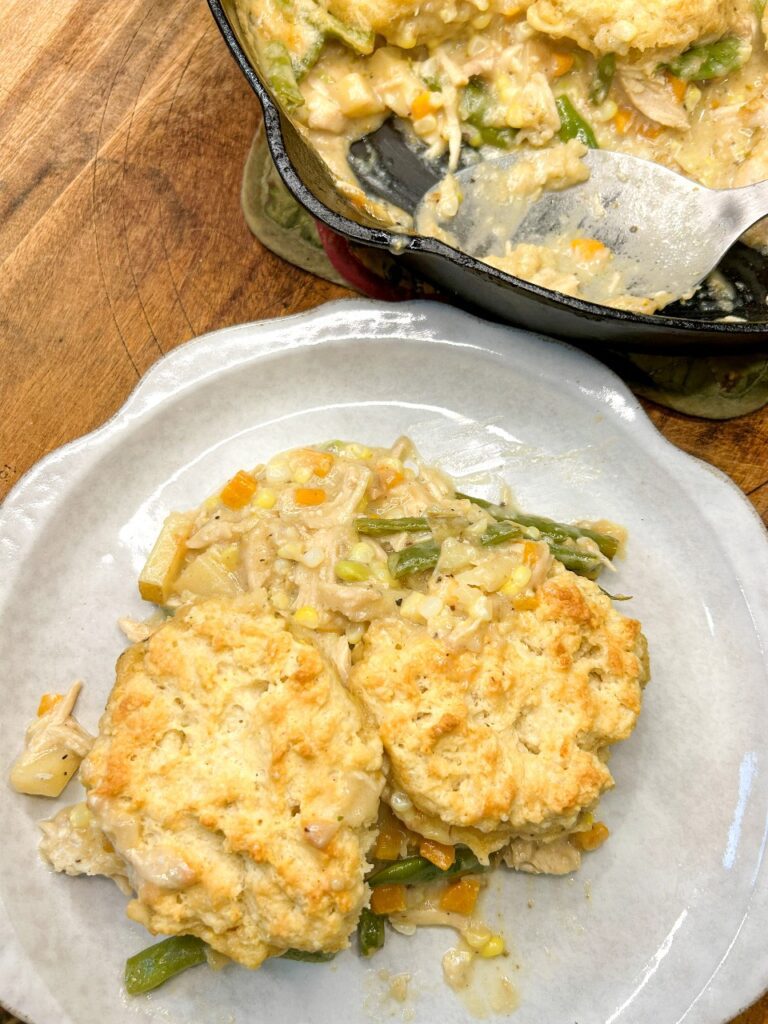 Scoop of chicken pot pie with creamy vegetables and a homemade biscuit.