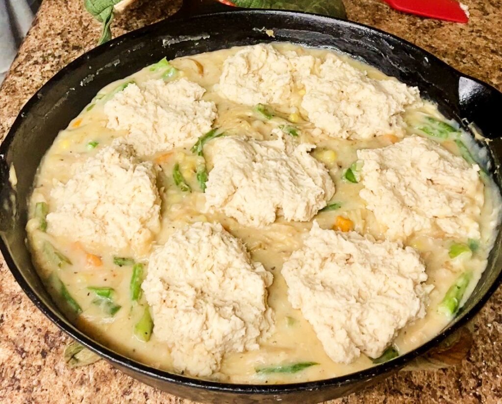 Cast iron skillet filled with creamy chicken pot pie and biscuit topping.